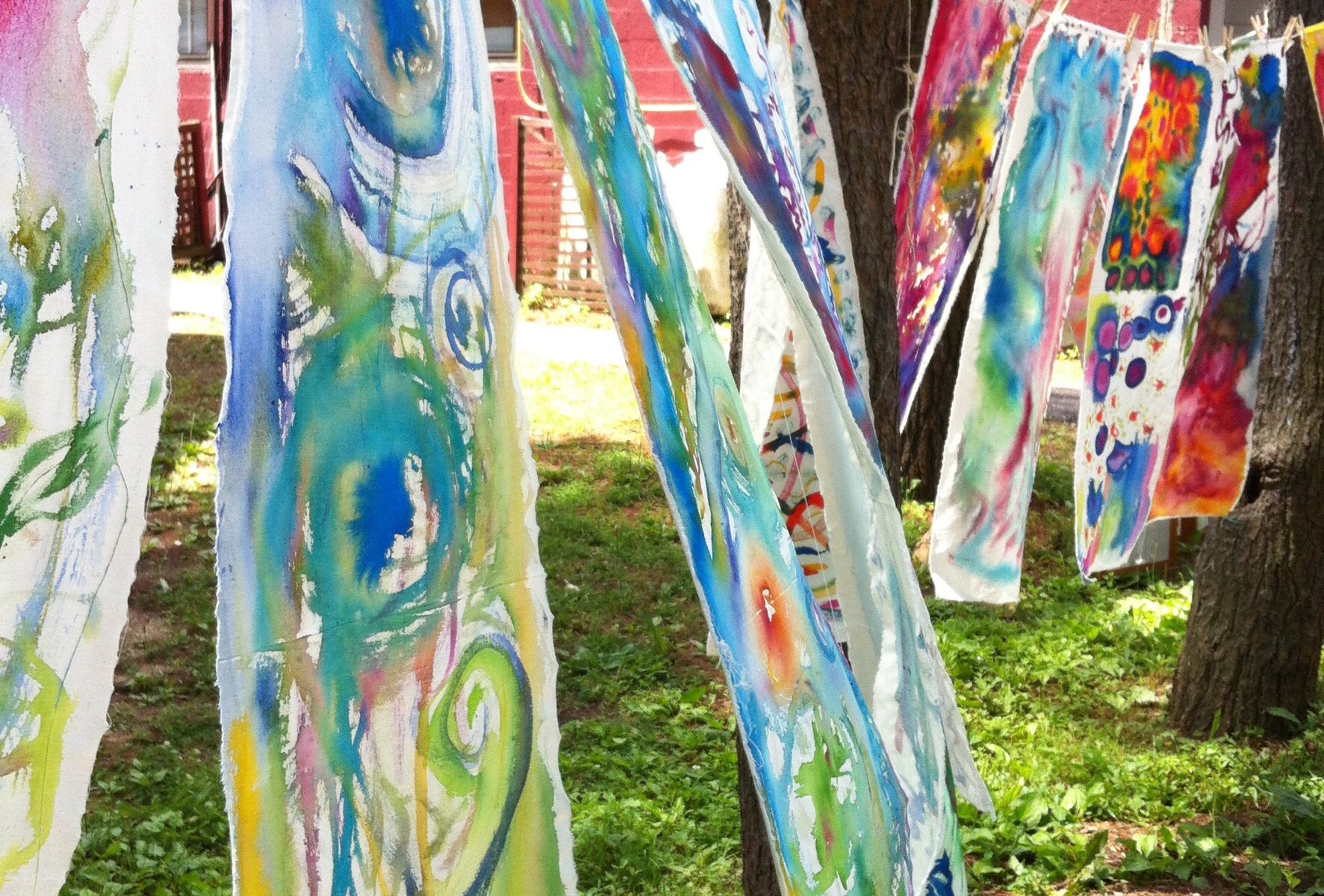 A line of colorful scarves hanging on a tree.