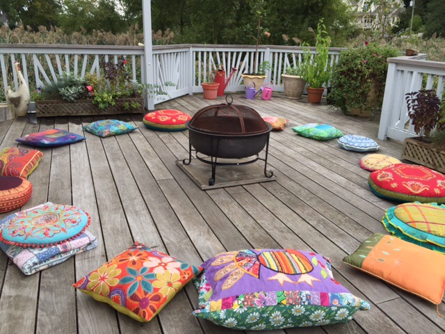 A fire pit on the deck with colorful pillows.